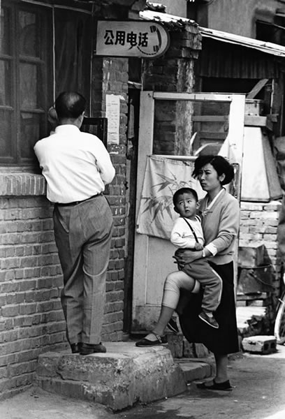 79.抱着孩子的妇女，面对一直抱着公共电话的人.jpg